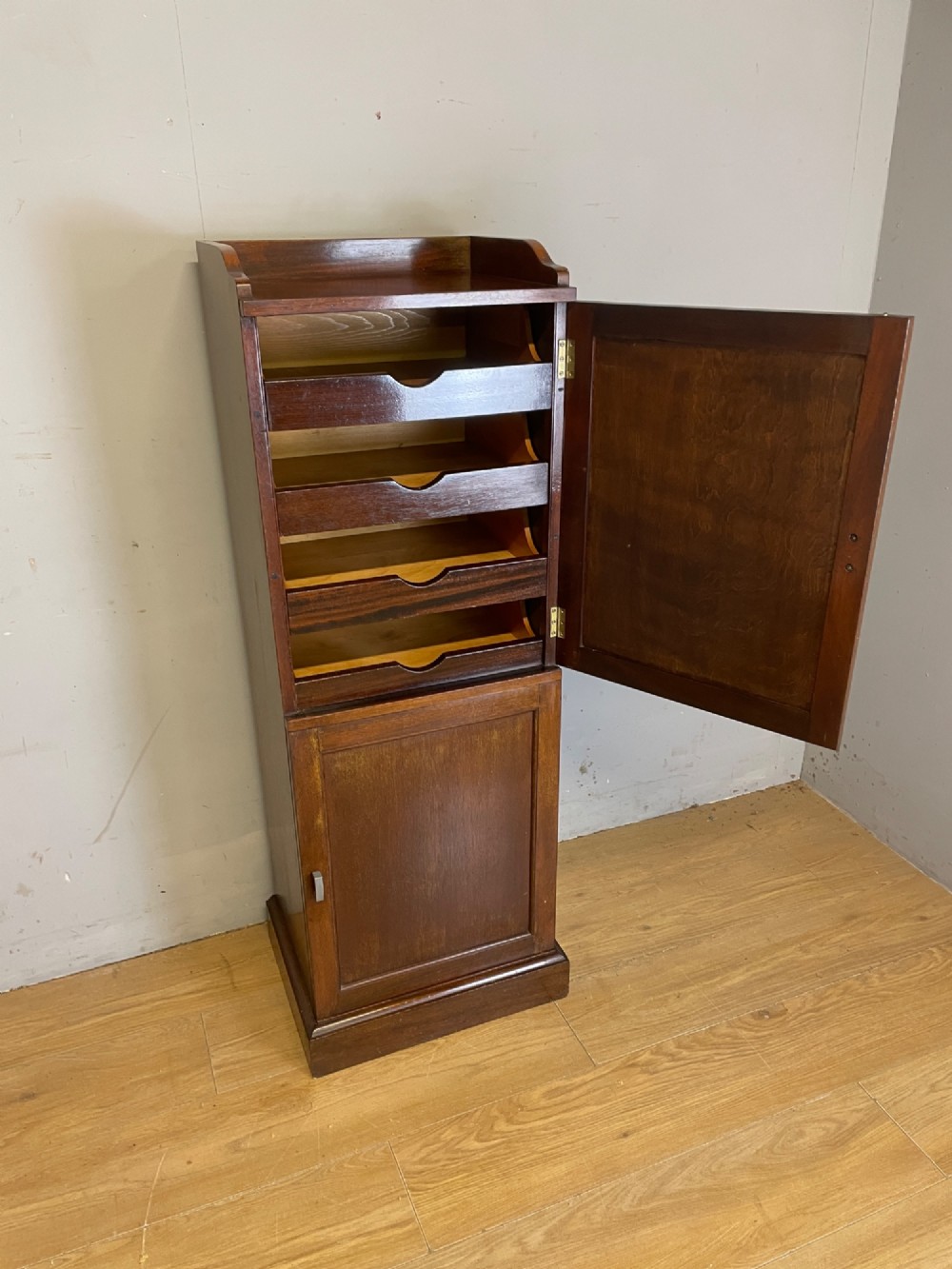 A tall, narrow early 20th-century solid mahogany filing cabinet featuring two panelled door drawers with metal handles, a plinth base, and a raised gallery top. View III
