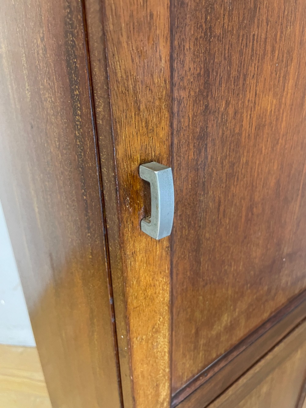 A tall, narrow early 20th-century solid mahogany filing cabinet featuring two panelled door drawers with metal handles, a plinth base, and a raised gallery top. View VIII