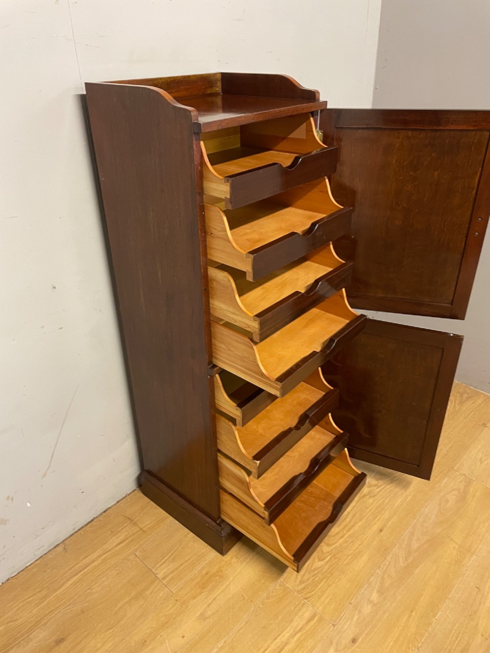 A tall, narrow early 20th-century solid mahogany filing cabinet featuring two panelled door drawers with metal handles, a plinth base, and a raised gallery top. View XI
