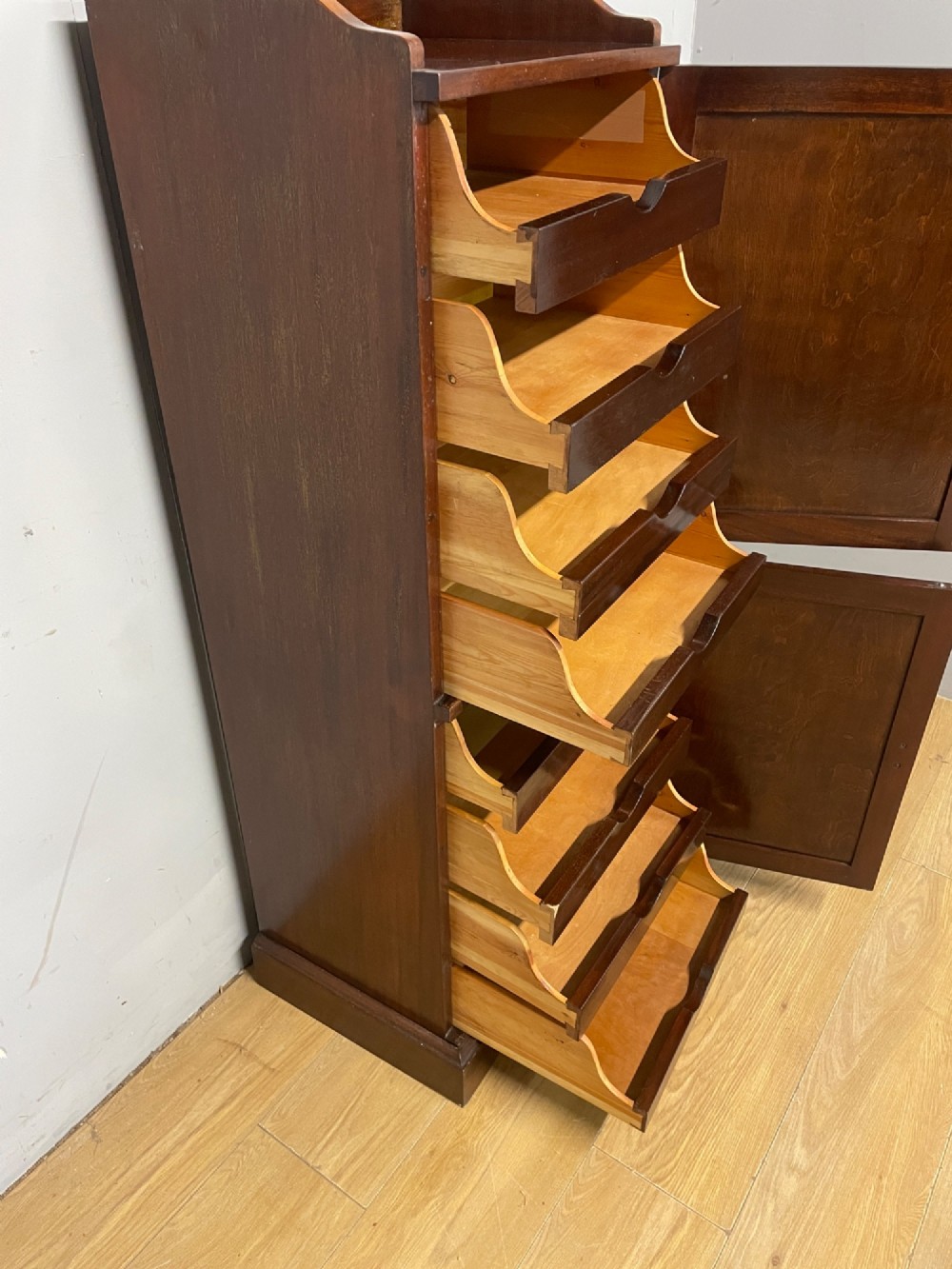 A tall, narrow early 20th-century solid mahogany filing cabinet featuring two panelled door drawers with metal handles, a plinth base, and a raised gallery top. View XII