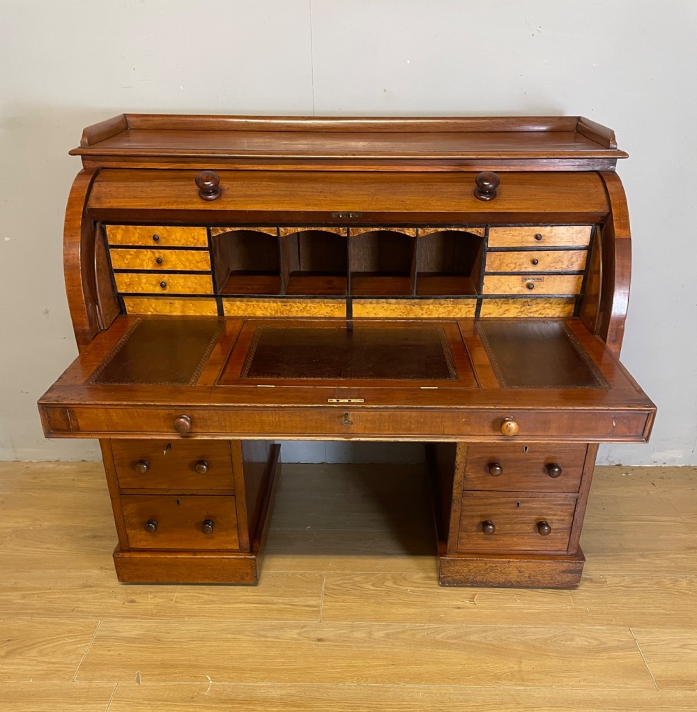 A nineteenth-century mahogany cylinder pedestal desk featuring a curved roll-down front, an extendable leather-lined writing slope, small interior drawers, and twin pedestals. View II