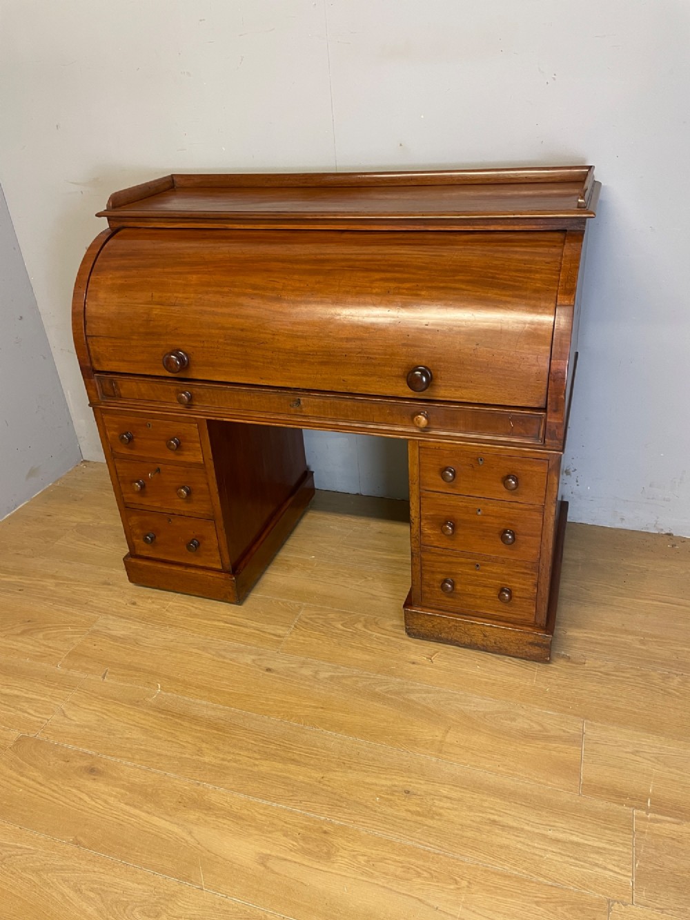 A nineteenth-century mahogany cylinder pedestal desk featuring a curved roll-down front, an extendable leather-lined writing slope, small interior drawers, and twin pedestals. View III