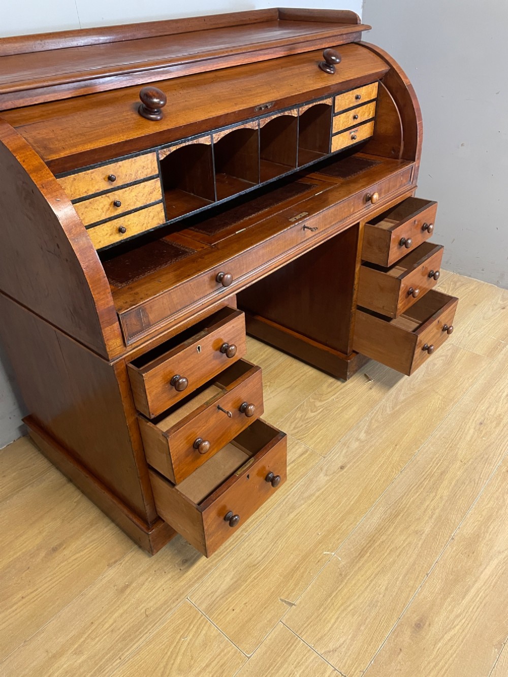 A nineteenth-century mahogany cylinder pedestal desk featuring a curved roll-down front, an extendable leather-lined writing slope, small interior drawers, and twin pedestals. View VII