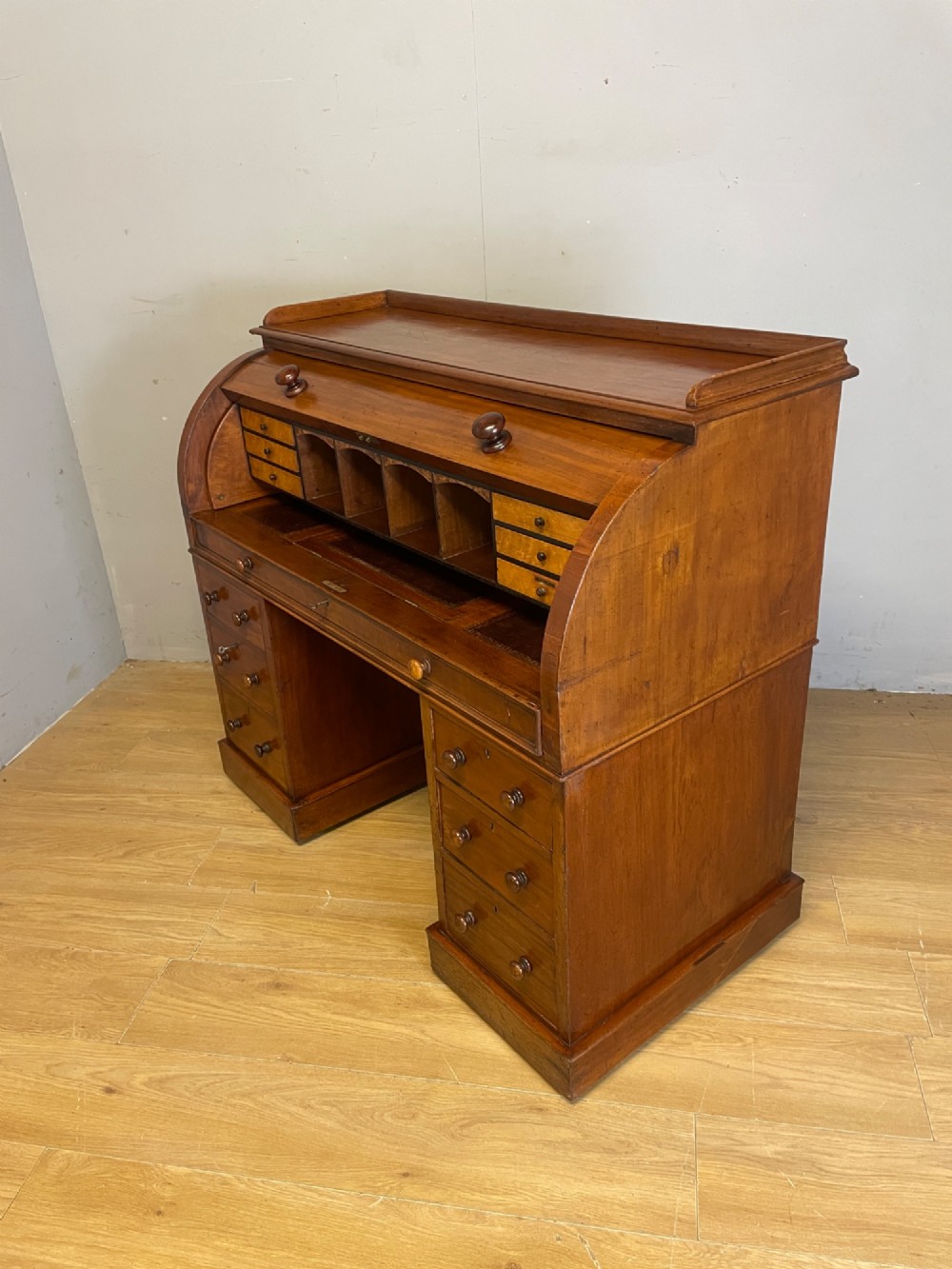 A nineteenth-century mahogany cylinder pedestal desk featuring a curved roll-down front, an extendable leather-lined writing slope, small interior drawers, and twin pedestals. View VIII