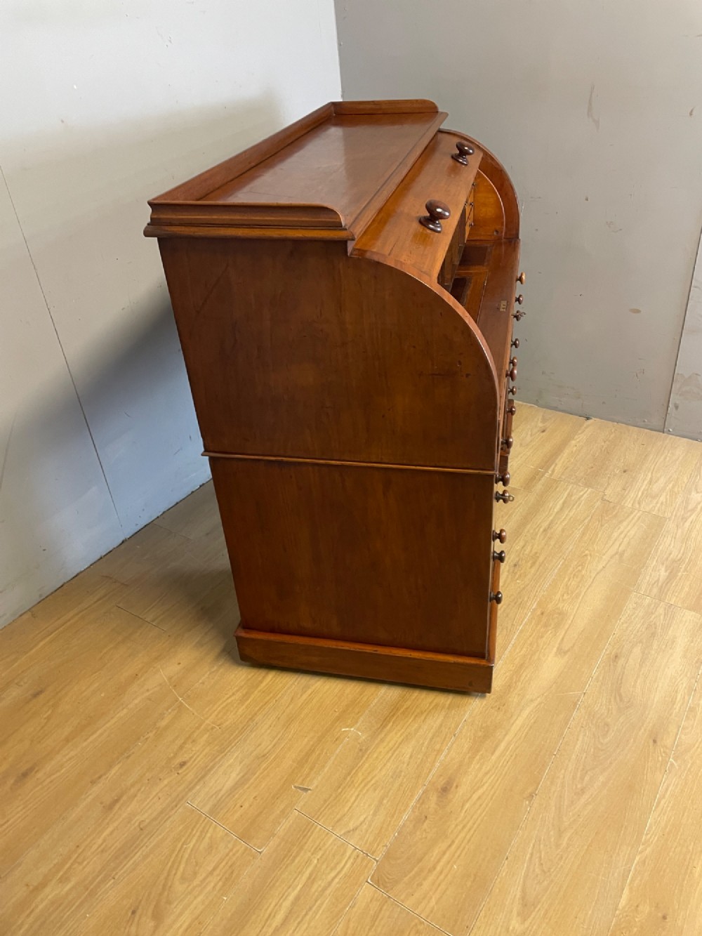 A nineteenth-century mahogany cylinder pedestal desk featuring a curved roll-down front, an extendable leather-lined writing slope, small interior drawers, and twin pedestals. View IX