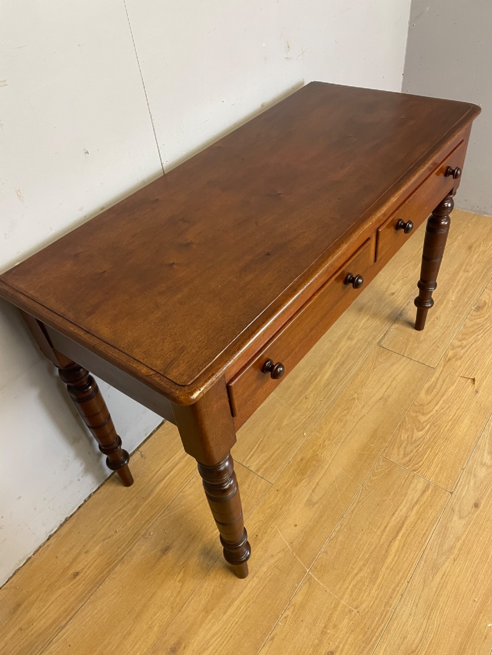 A 19th-century mahogany side table featuring a rectangular top, two front drawers with turned wooden knobs, and four ring-turned legs. View II