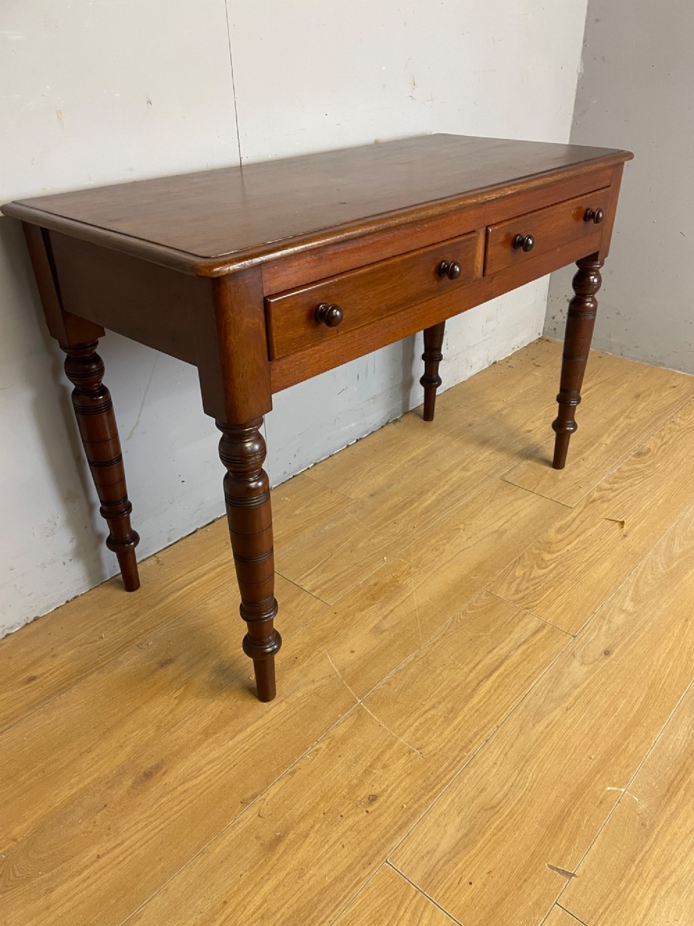 A 19th-century mahogany side table featuring a rectangular top, two front drawers with turned wooden knobs, and four ring-turned legs. View III