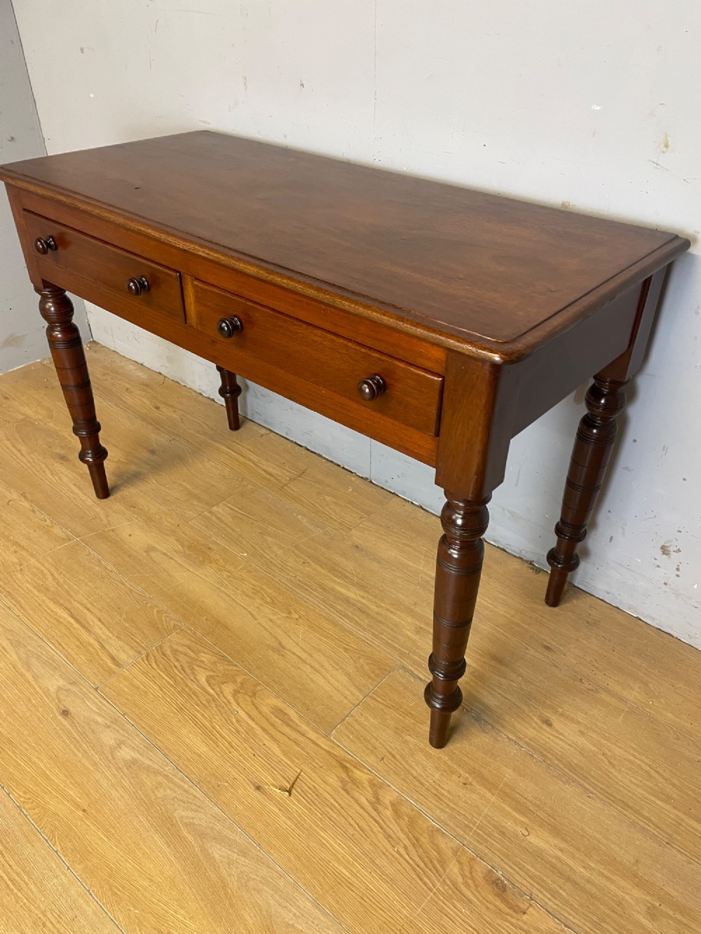 A 19th-century mahogany side table featuring a rectangular top, two front drawers with turned wooden knobs, and four ring-turned legs. View IV