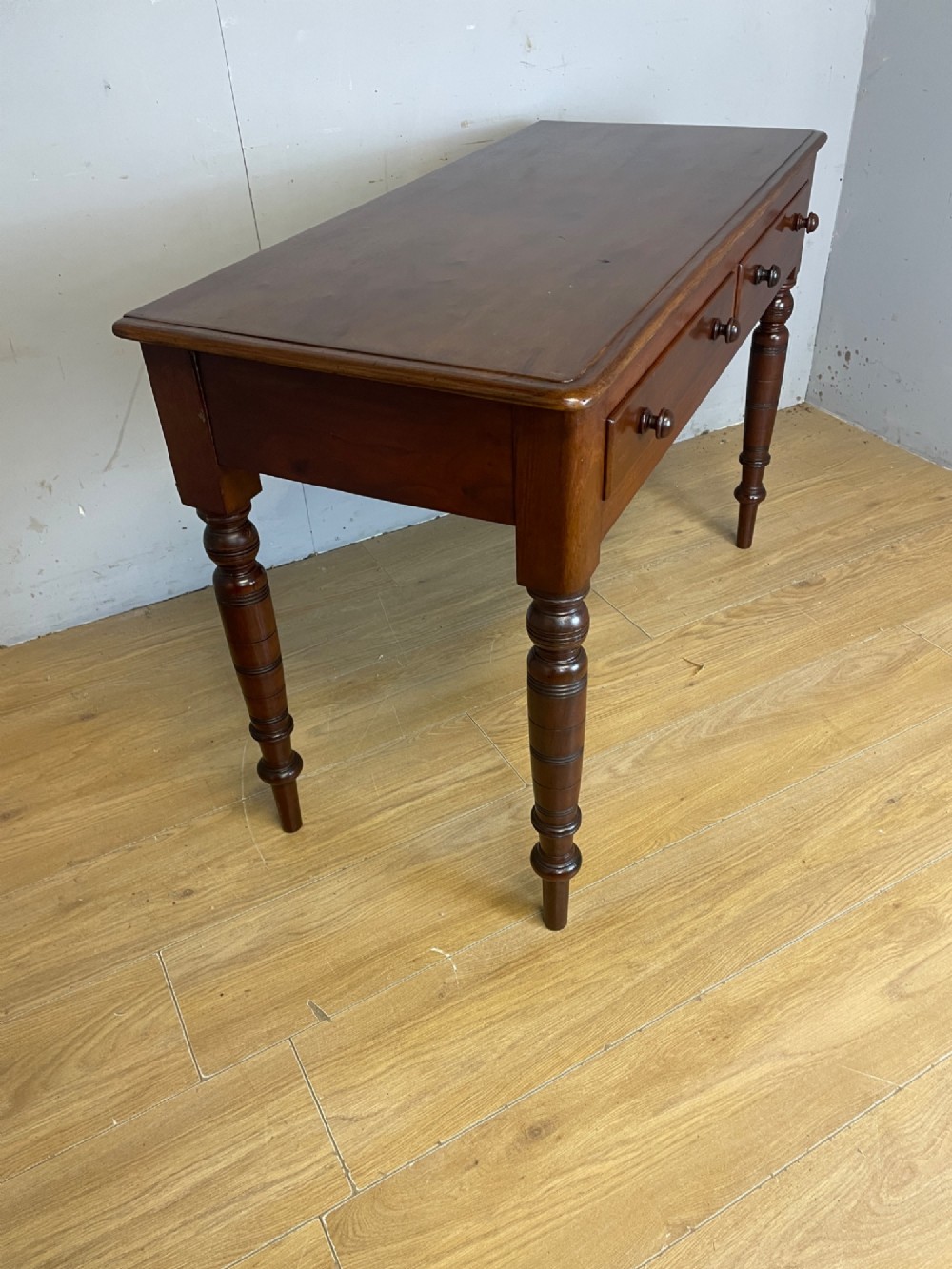 A 19th-century mahogany side table featuring a rectangular top, two front drawers with turned wooden knobs, and four ring-turned legs. View VI
