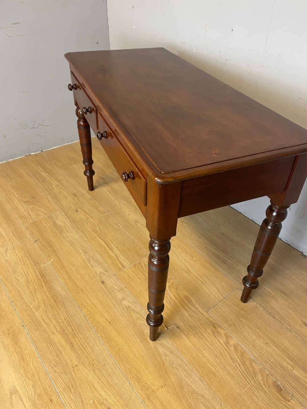A 19th-century mahogany side table featuring a rectangular top, two front drawers with turned wooden knobs, and four ring-turned legs. View VII