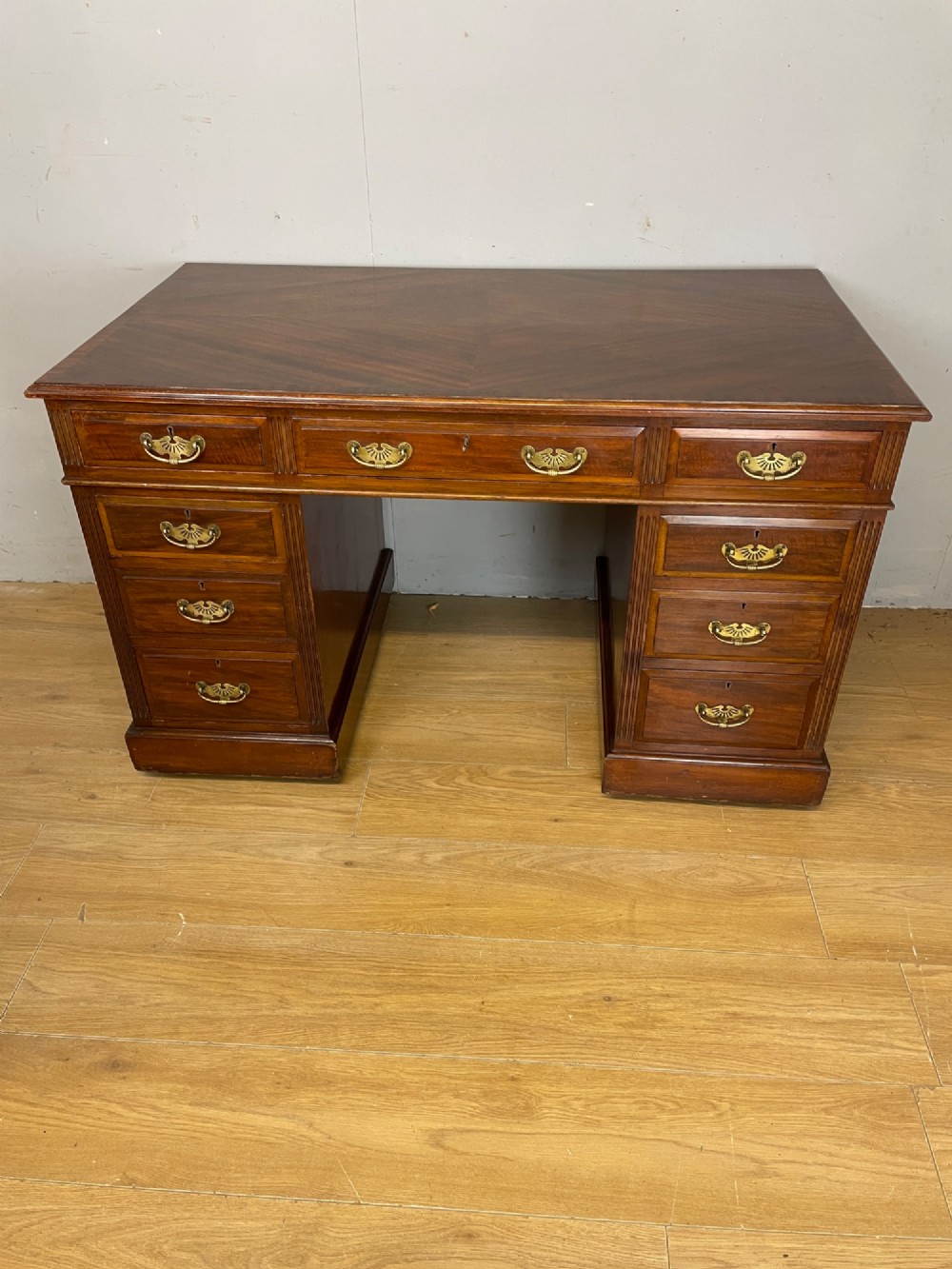 A nineteenth-century mahogany twin pedestal desk featuring nine drawers with brass swan-neck handles and a rectangular veneered top surface. View II