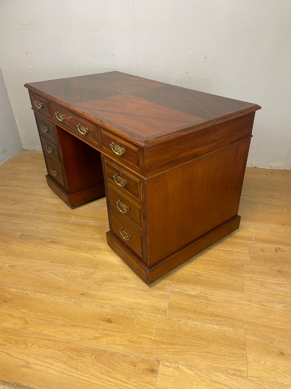 A nineteenth-century mahogany twin pedestal desk featuring nine drawers with brass swan-neck handles and a rectangular veneered top surface. View VII