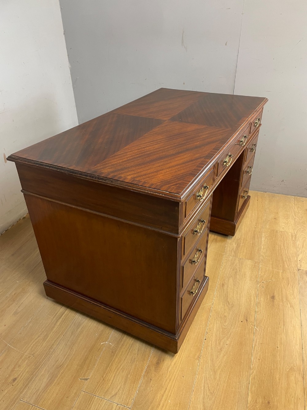 A nineteenth-century mahogany twin pedestal desk featuring nine drawers with brass swan-neck handles and a rectangular veneered top surface. View VIII