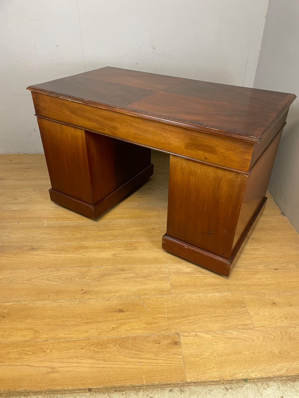 A nineteenth-century mahogany twin pedestal desk featuring nine drawers with brass swan-neck handles and a rectangular veneered top surface. View IX
