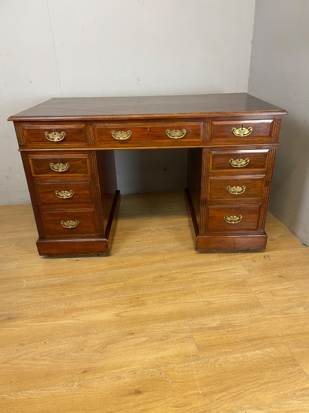 A nineteenth-century mahogany twin pedestal desk featuring nine drawers with brass swan-neck handles and a rectangular veneered top surface. View X