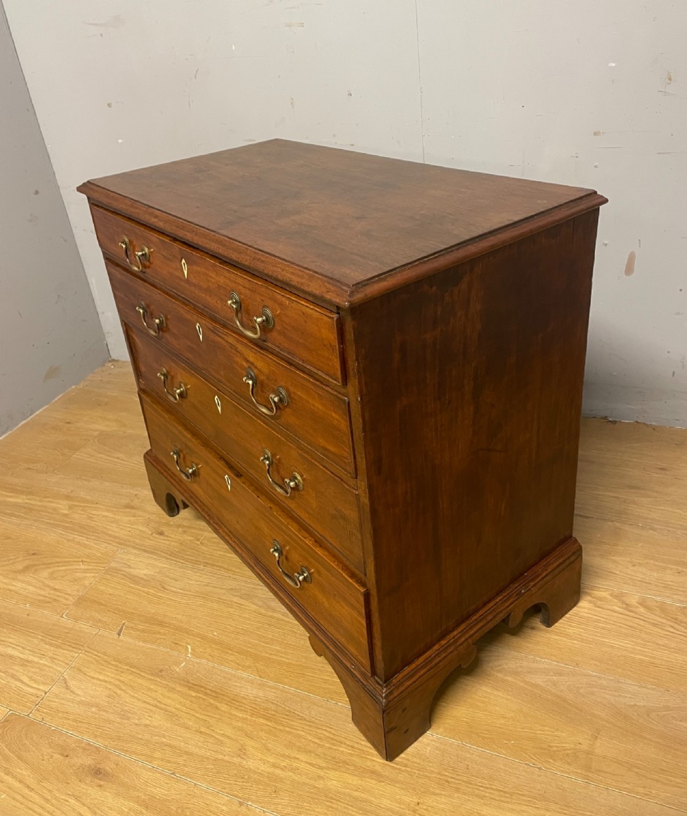 A George III period mahogany chest of drawers featuring four graduated drawers with brass swan-neck handles, diamond keyhole escutcheons, and bracket feet. View VI