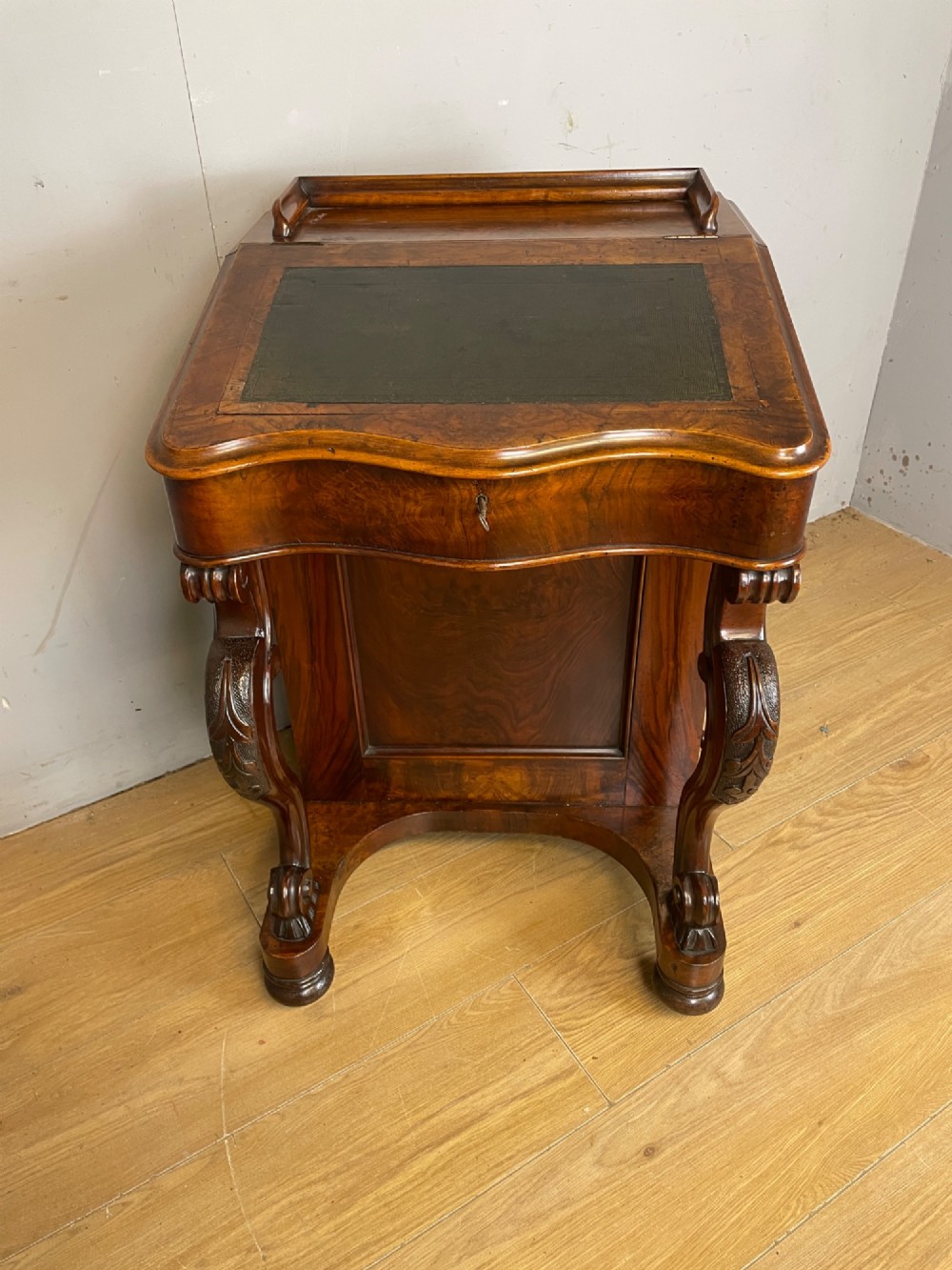 A late 19th-century walnut Davenport desk featuring a sloped leather writing top, carved cabriole front supports, and side drawers. View II