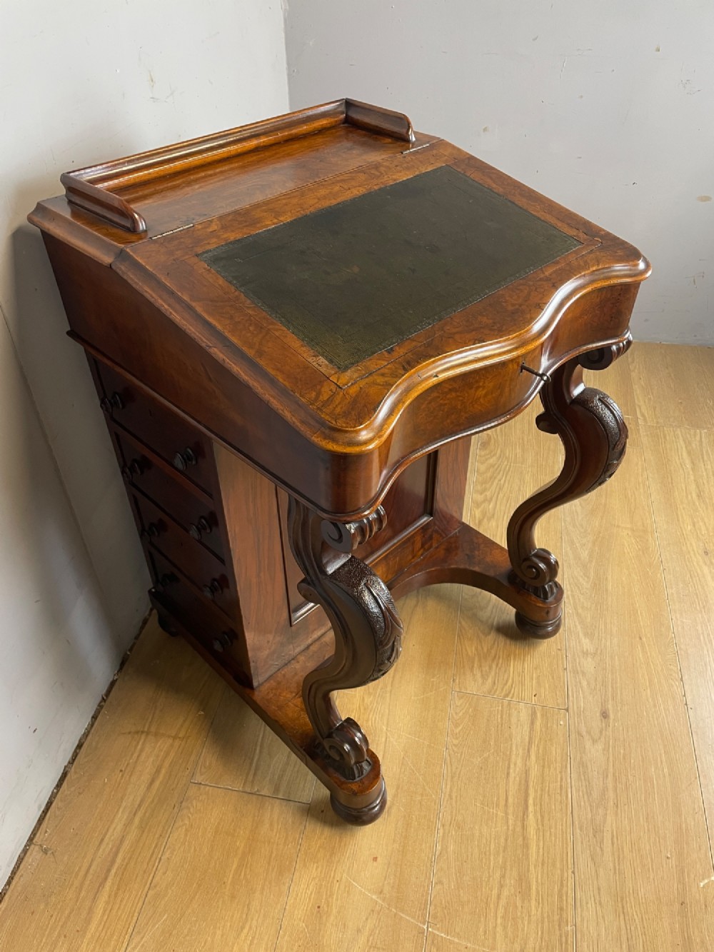 A late 19th-century walnut Davenport desk featuring a sloped leather writing top, carved cabriole front supports, and side drawers. View III
