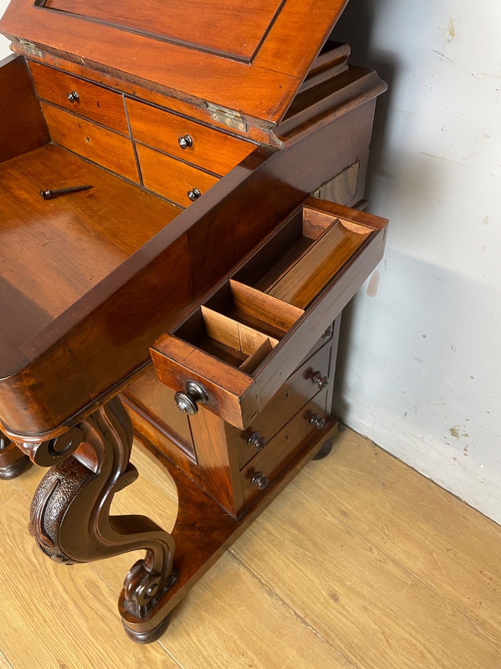 A late 19th-century walnut Davenport desk featuring a sloped leather writing top, carved cabriole front supports, and side drawers. View VI