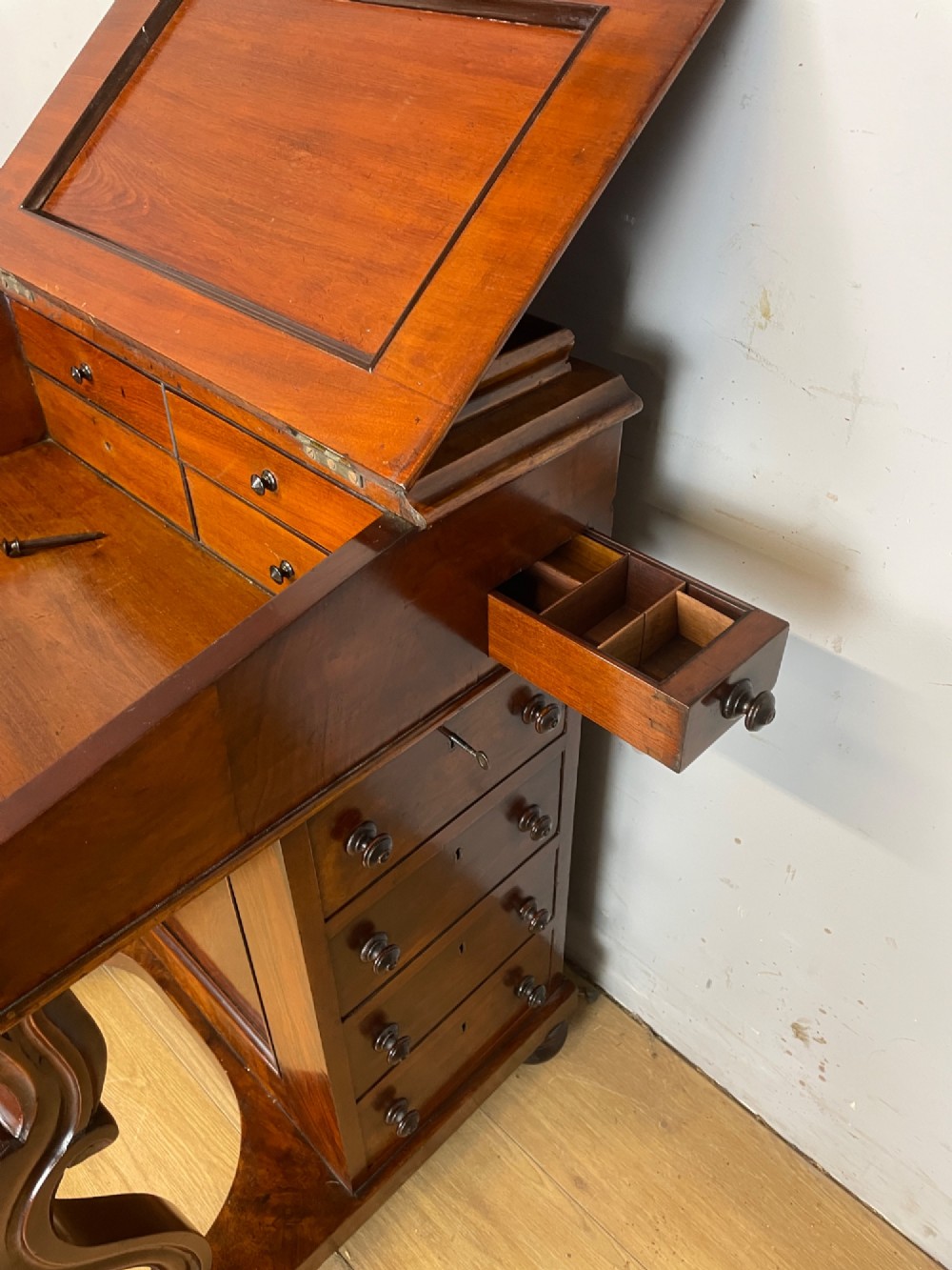 A late 19th-century walnut Davenport desk featuring a sloped leather writing top, carved cabriole front supports, and side drawers. View VII