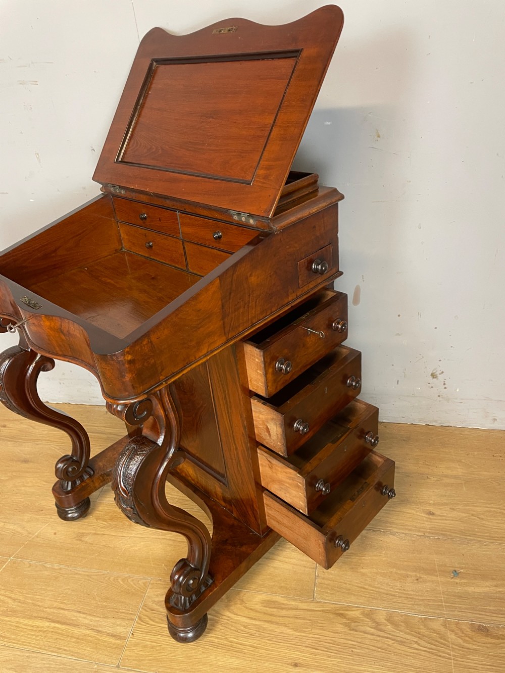 A late 19th-century walnut Davenport desk featuring a sloped leather writing top, carved cabriole front supports, and side drawers. View VIII