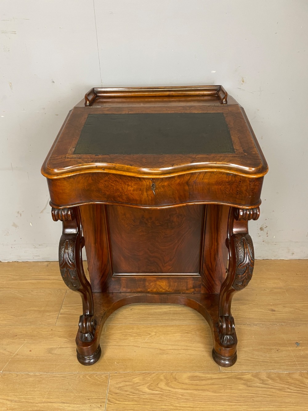 A late 19th-century walnut Davenport desk featuring a sloped leather writing top, carved cabriole front supports, and side drawers. View XIII