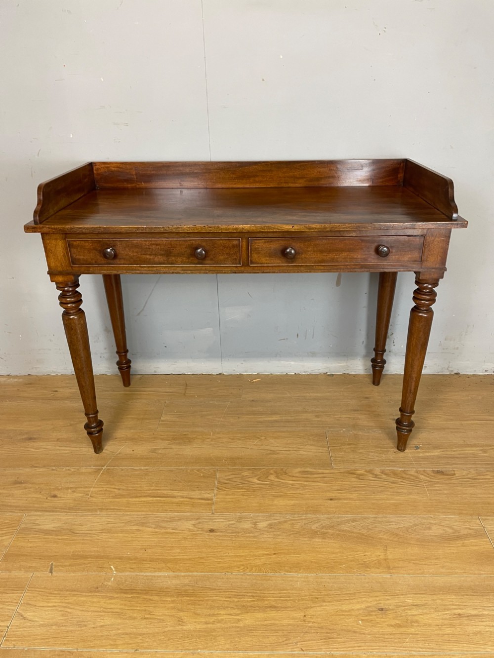 A nineteenth-century flame mahogany side table featuring a three-sided gallery top, two inline drawers with turned knobs, and four turned legs. View III