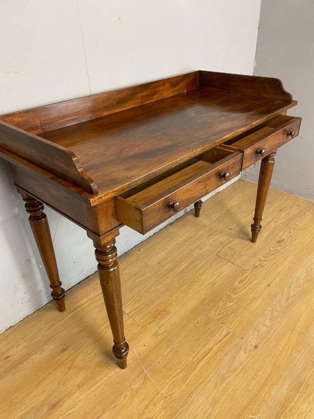 A nineteenth-century flame mahogany side table featuring a three-sided gallery top, two inline drawers with turned knobs, and four turned legs. View V