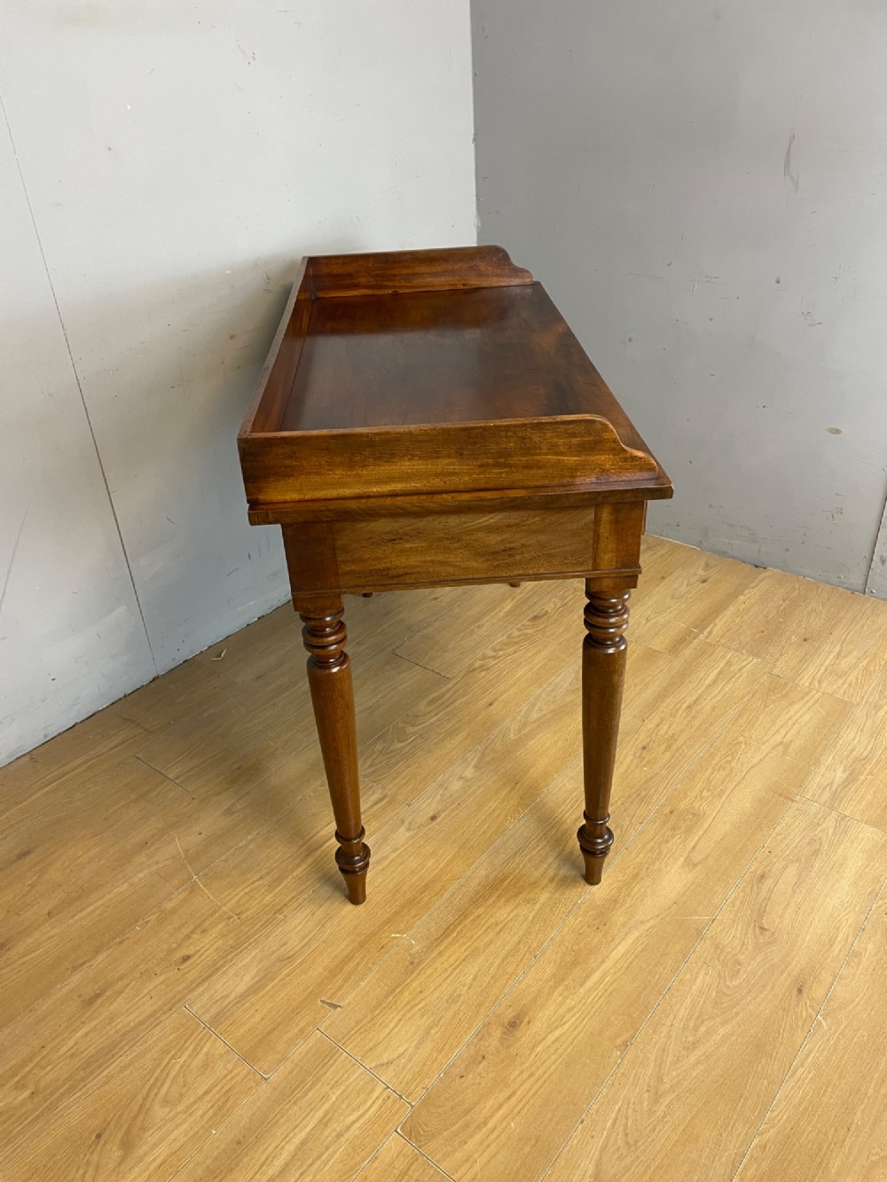 A nineteenth-century flame mahogany side table featuring a three-sided gallery top, two inline drawers with turned knobs, and four turned legs. View VII