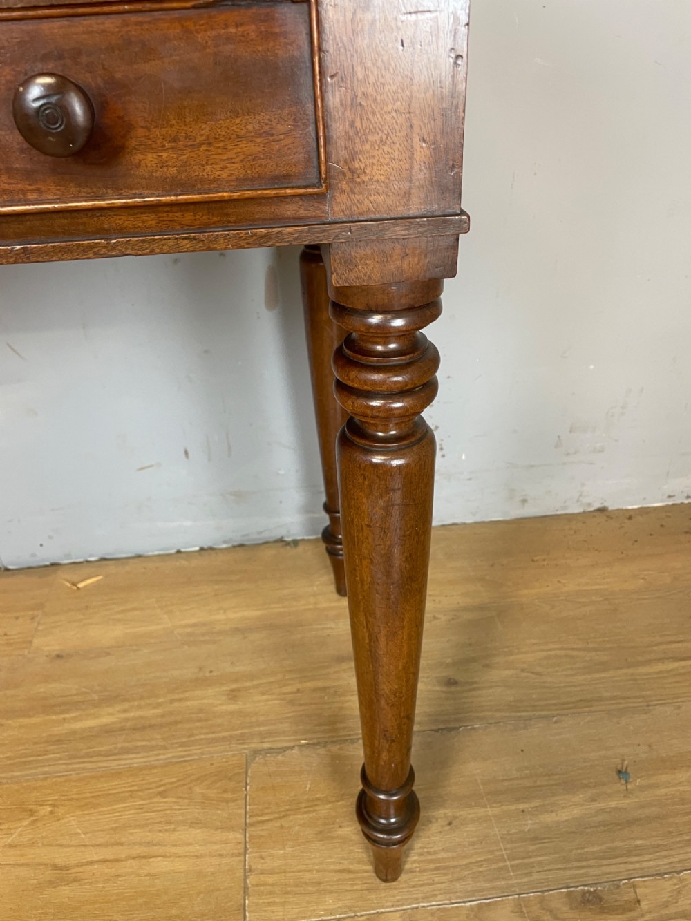 A nineteenth-century flame mahogany side table featuring a three-sided gallery top, two inline drawers with turned knobs, and four turned legs. View IX