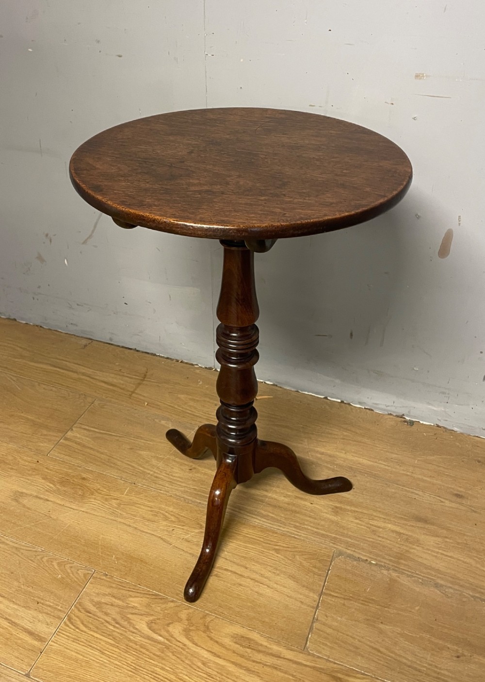 A Georgian mahogany wine table featuring a circular tilt top supported by a turned central pillar and three splayed legs.