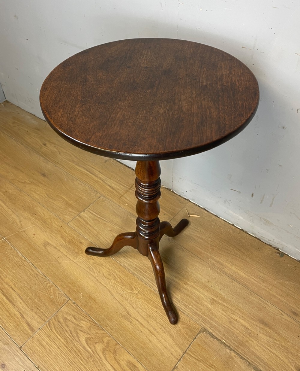 A Georgian mahogany wine table featuring a circular tilt top supported by a turned central pillar and three splayed legs. View II