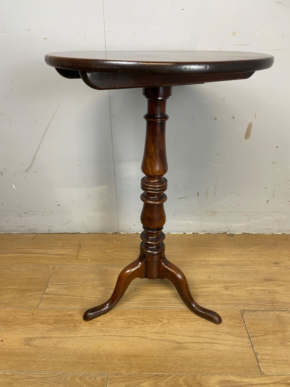 A Georgian mahogany wine table featuring a circular tilt top supported by a turned central pillar and three splayed legs. View V