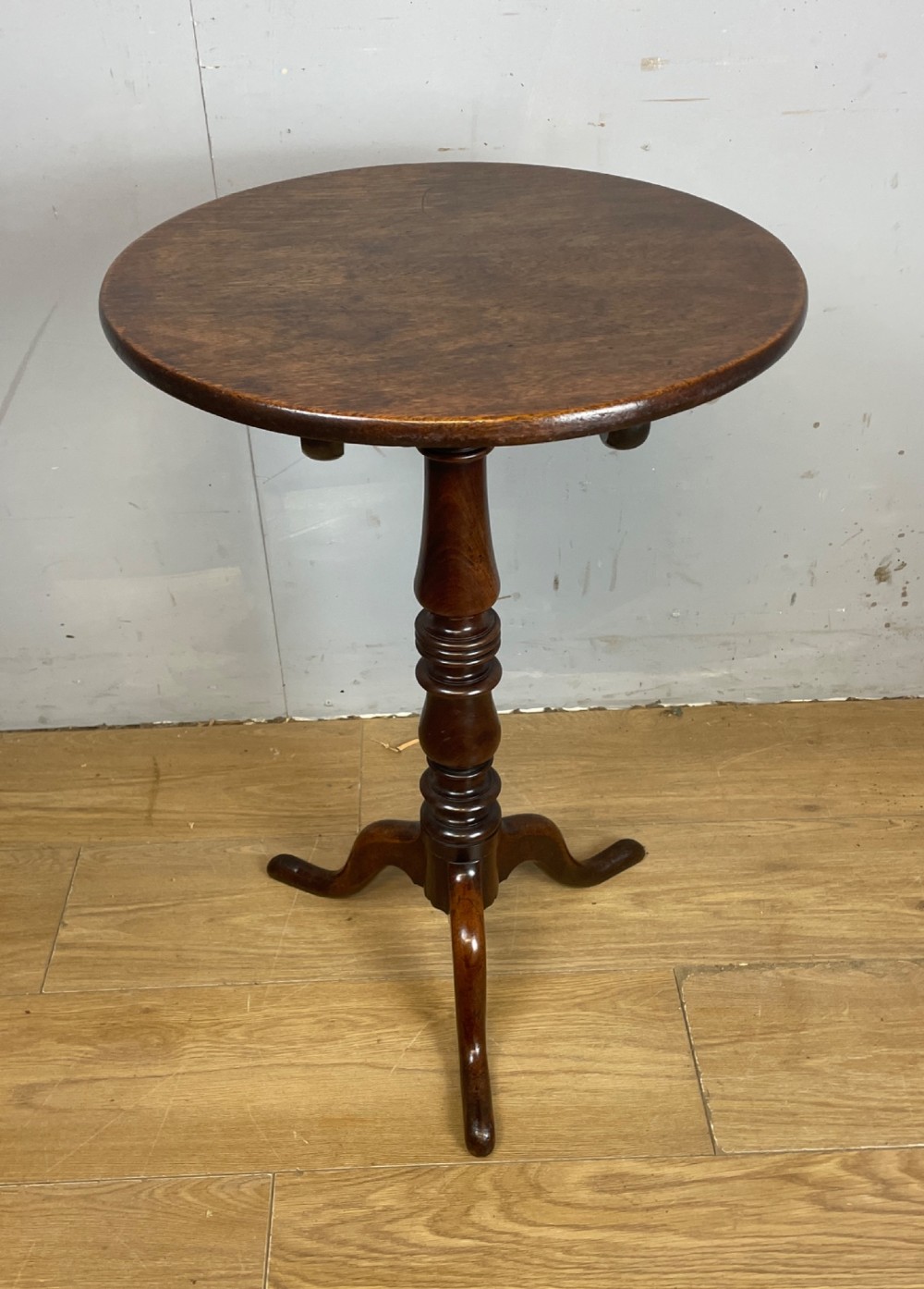 A Georgian mahogany wine table featuring a circular tilt top supported by a turned central pillar and three splayed legs. View X