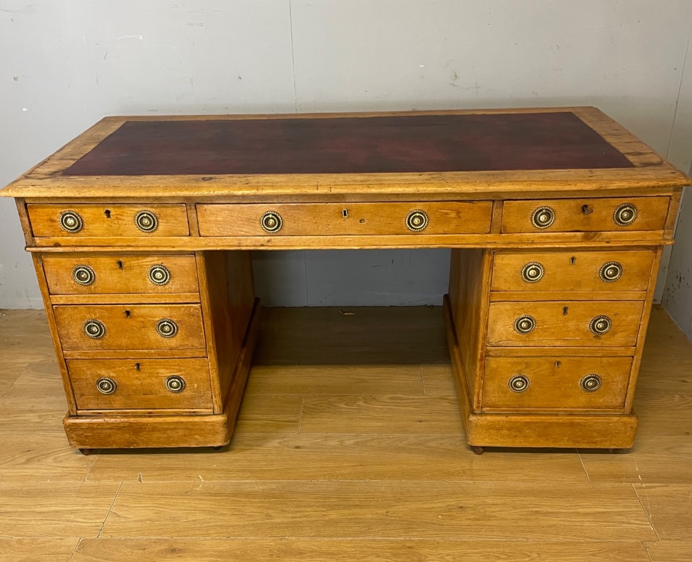A Victorian three-part pine twin pedestal desk featuring a burgundy leather writing inset, multiple brass ring-pull drawers, and a plinth base. View II