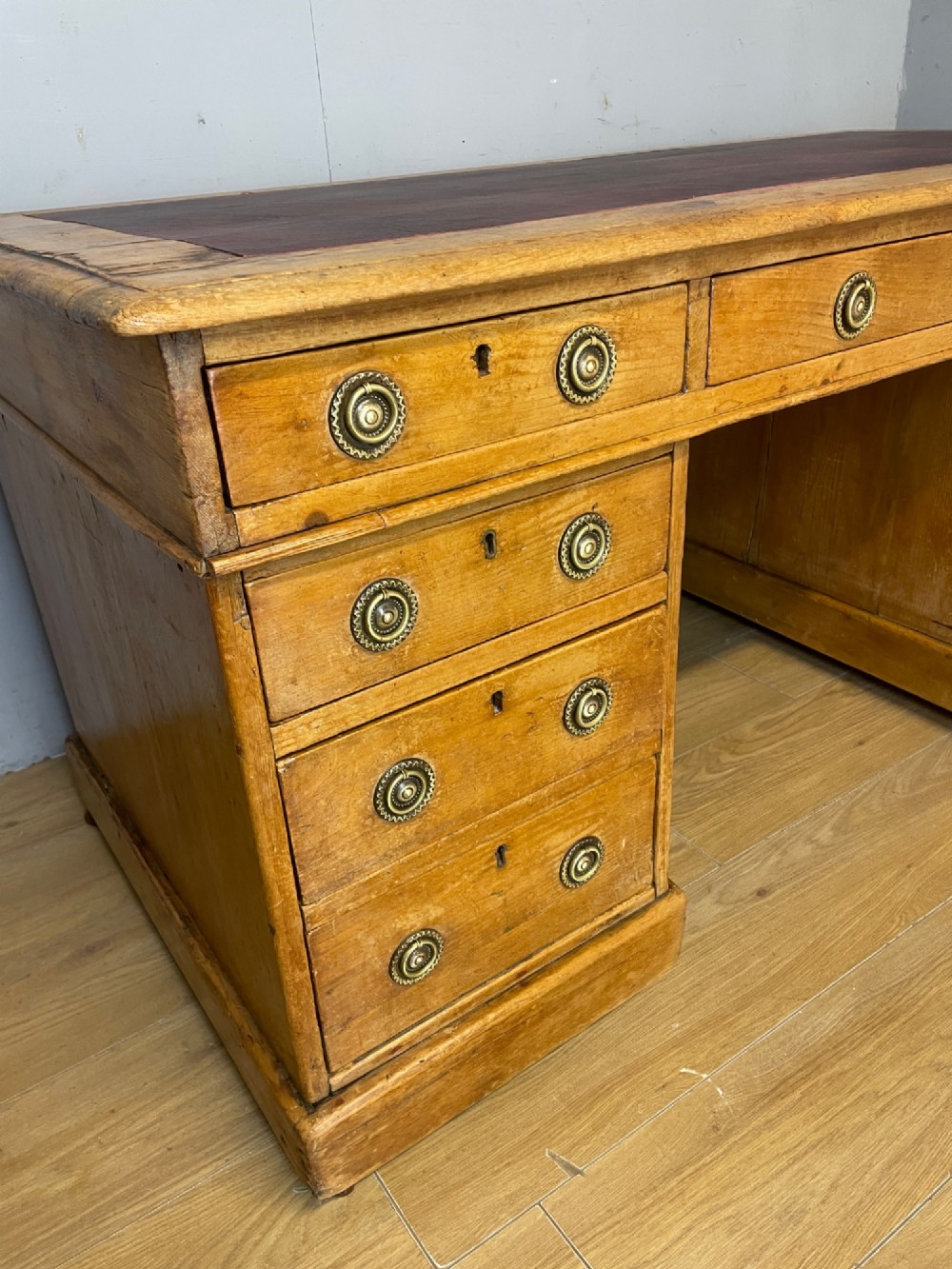 A Victorian three-part pine twin pedestal desk featuring a burgundy leather writing inset, multiple brass ring-pull drawers, and a plinth base. View V