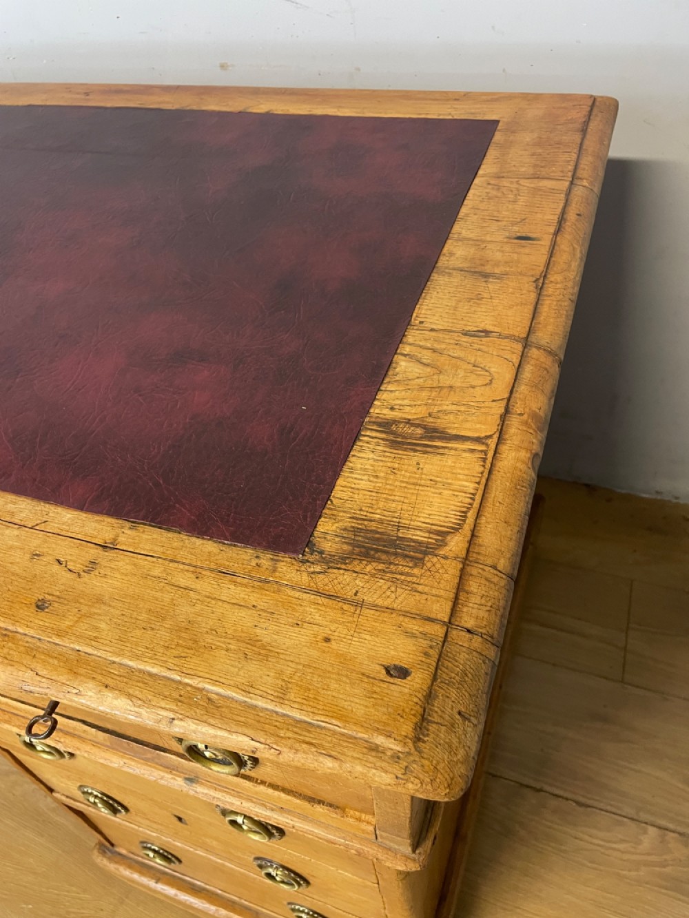 A Victorian three-part pine twin pedestal desk featuring a burgundy leather writing inset, multiple brass ring-pull drawers, and a plinth base. View VII