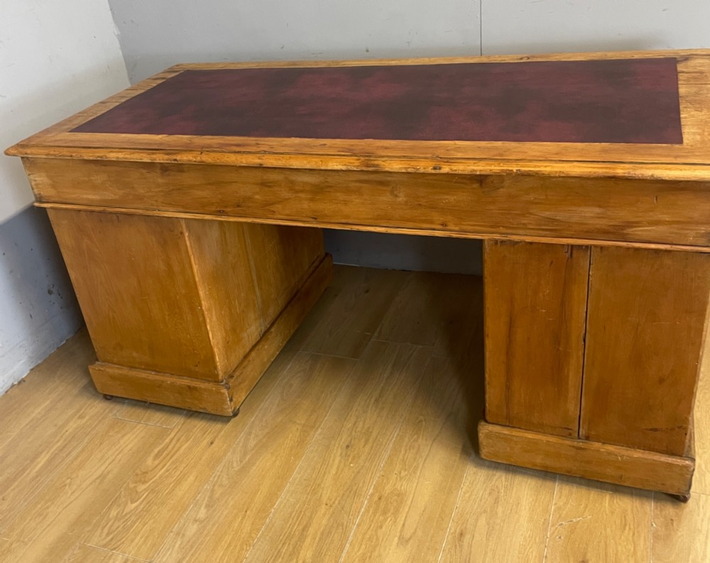 A Victorian three-part pine twin pedestal desk featuring a burgundy leather writing inset, multiple brass ring-pull drawers, and a plinth base. View XI