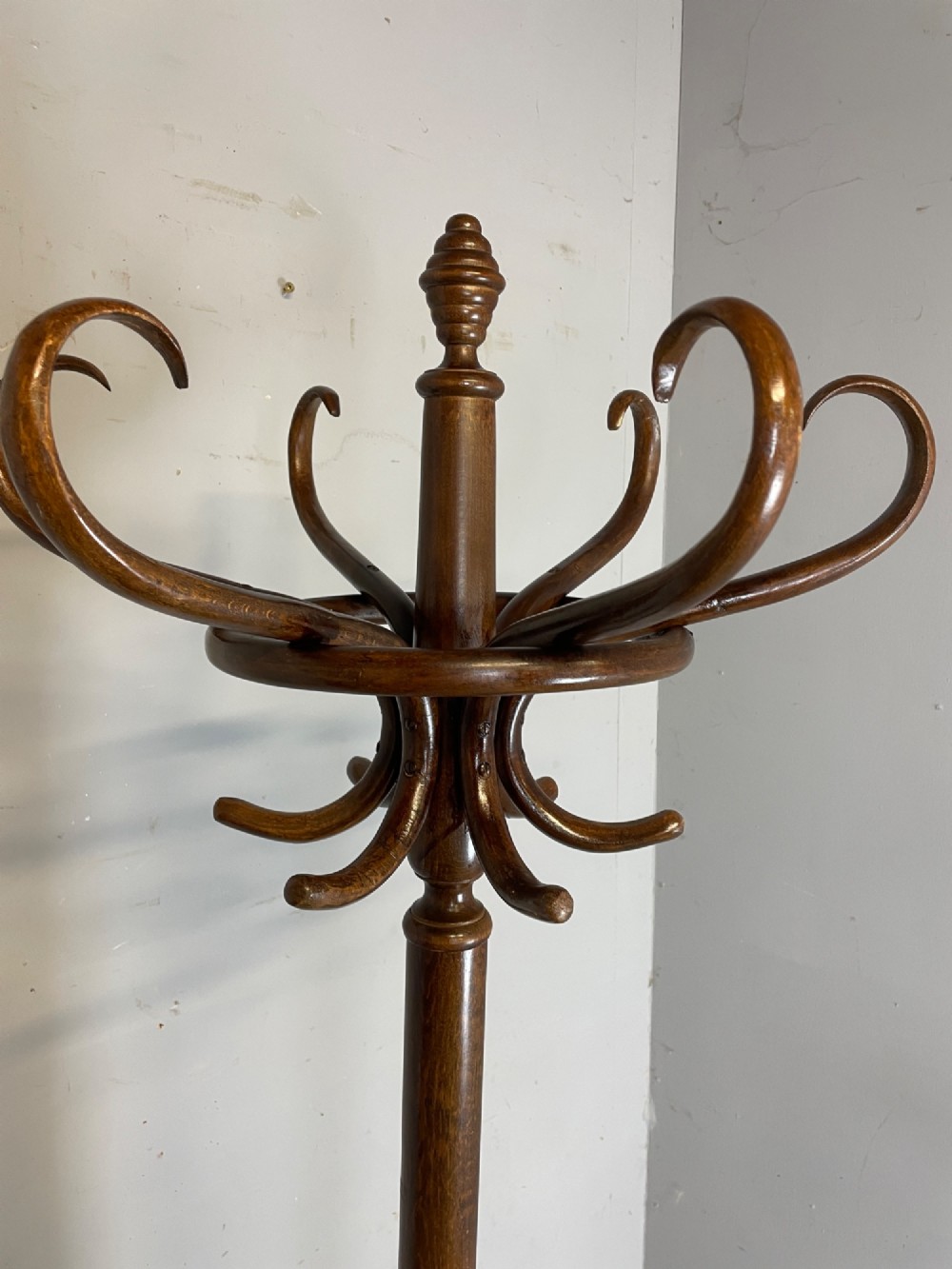 A tall dark brown bentwood freestanding coat and stick stand featuring curved upper hooks and a circular umbrella holder base. View III
