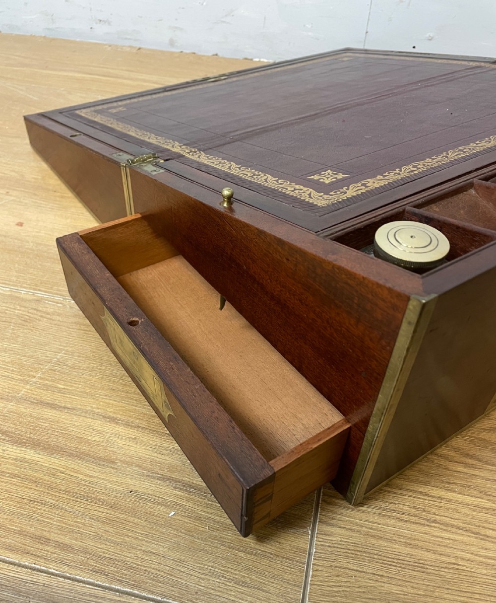 A 19th-century mahogany campaign writing slope featuring brass corner mounts, candle holders, and a gold-tooled burgundy leather writing surface. View VI