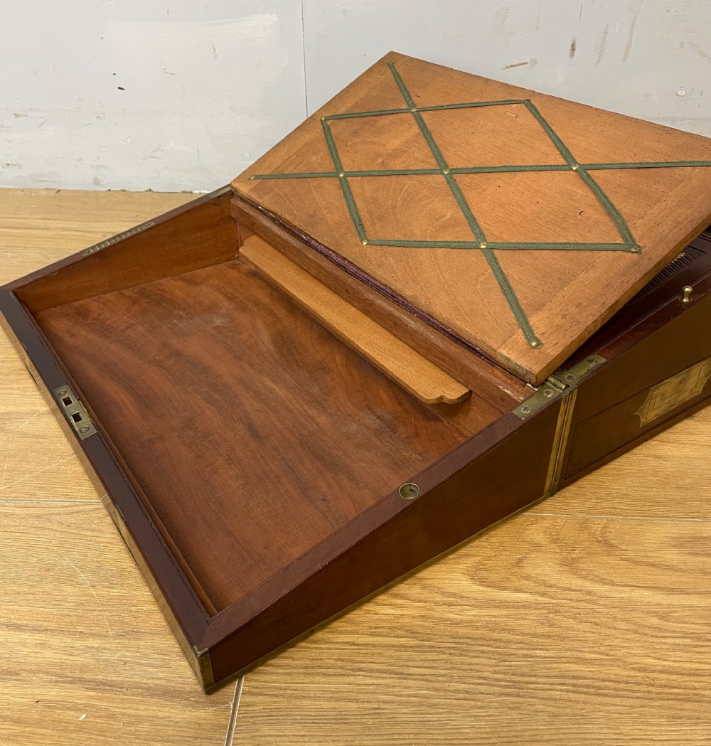 A 19th-century mahogany campaign writing slope featuring brass corner mounts, candle holders, and a gold-tooled burgundy leather writing surface. View IX