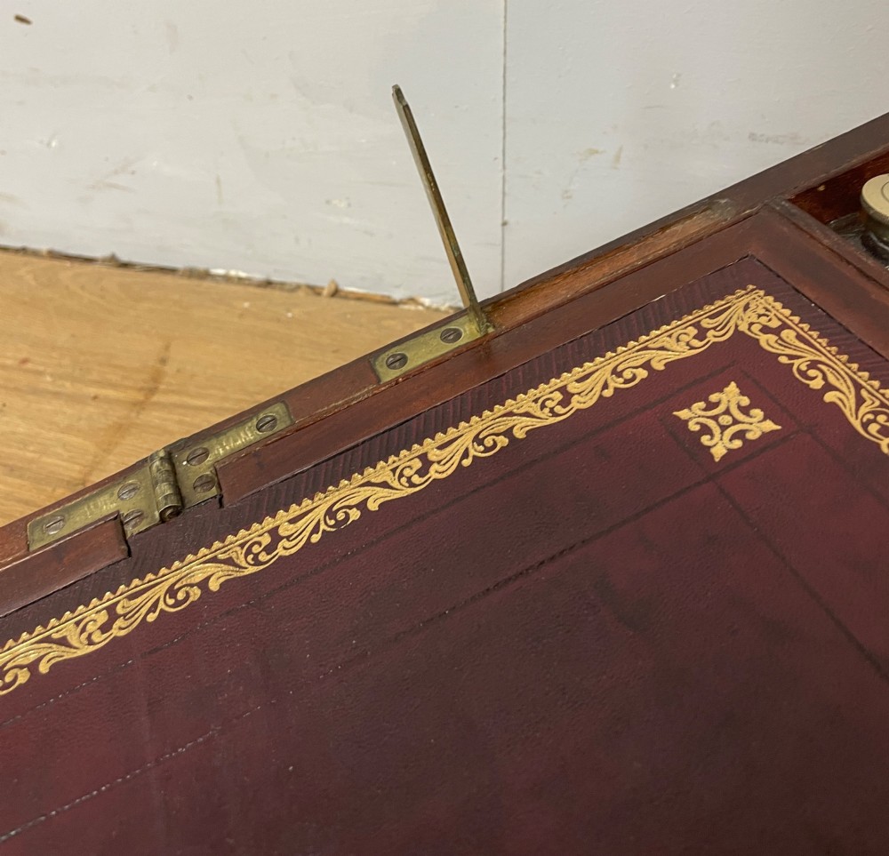 A 19th-century mahogany campaign writing slope featuring brass corner mounts, candle holders, and a gold-tooled burgundy leather writing surface. View X