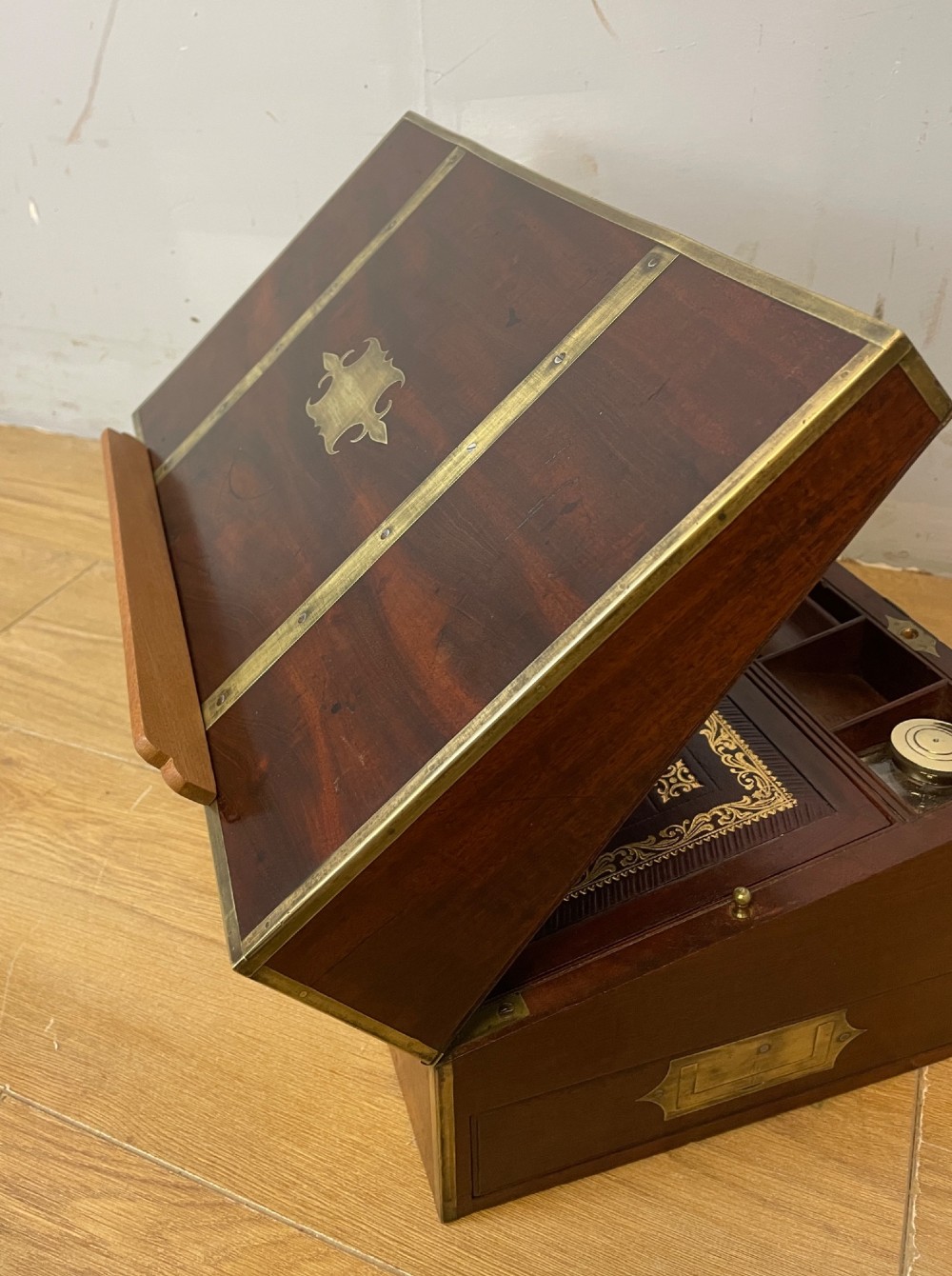 A 19th-century mahogany campaign writing slope featuring brass corner mounts, candle holders, and a gold-tooled burgundy leather writing surface. View XI