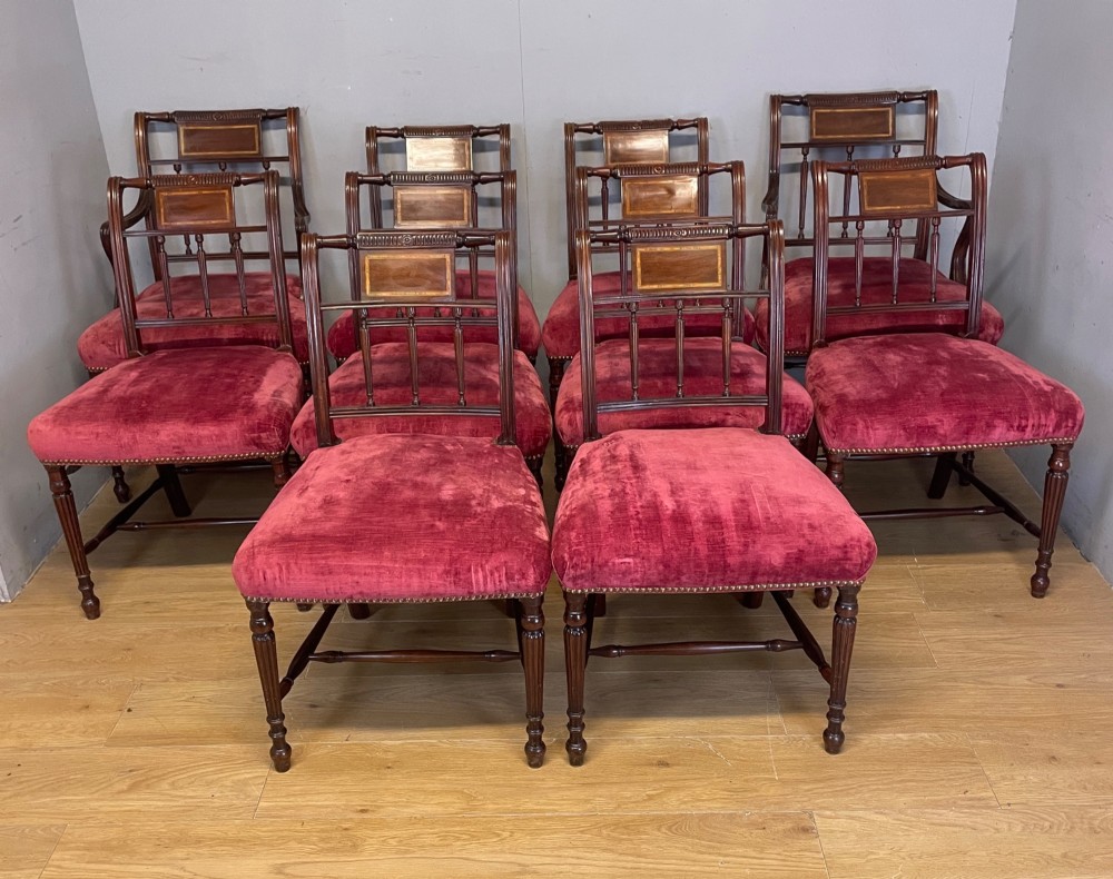 A set of ten nineteenth-century mahogany dining chairs featuring rectangular inlaid backrests, spindle uprights, and red velvet upholstered seats with brass stud detailing. View II