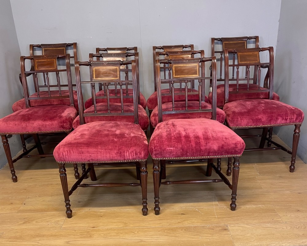 A set of ten nineteenth-century mahogany dining chairs featuring rectangular inlaid backrests, spindle uprights, and red velvet upholstered seats with brass stud detailing. View III