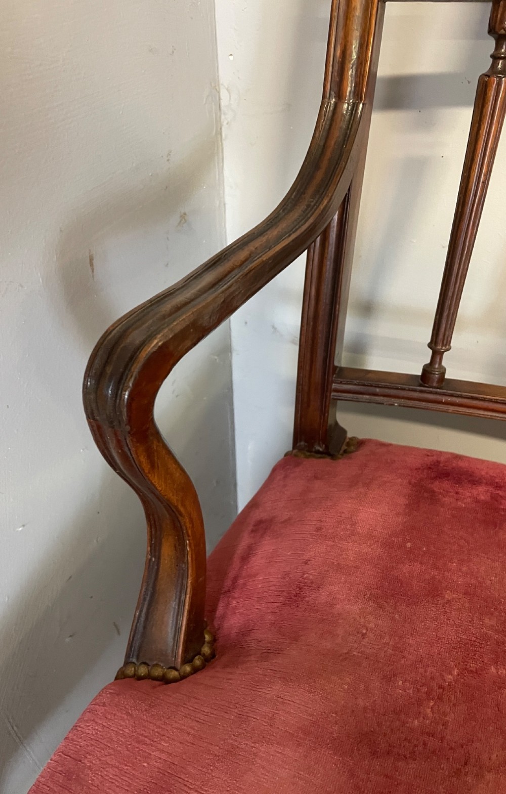 A set of ten nineteenth-century mahogany dining chairs featuring rectangular inlaid backrests, spindle uprights, and red velvet upholstered seats with brass stud detailing. View VI