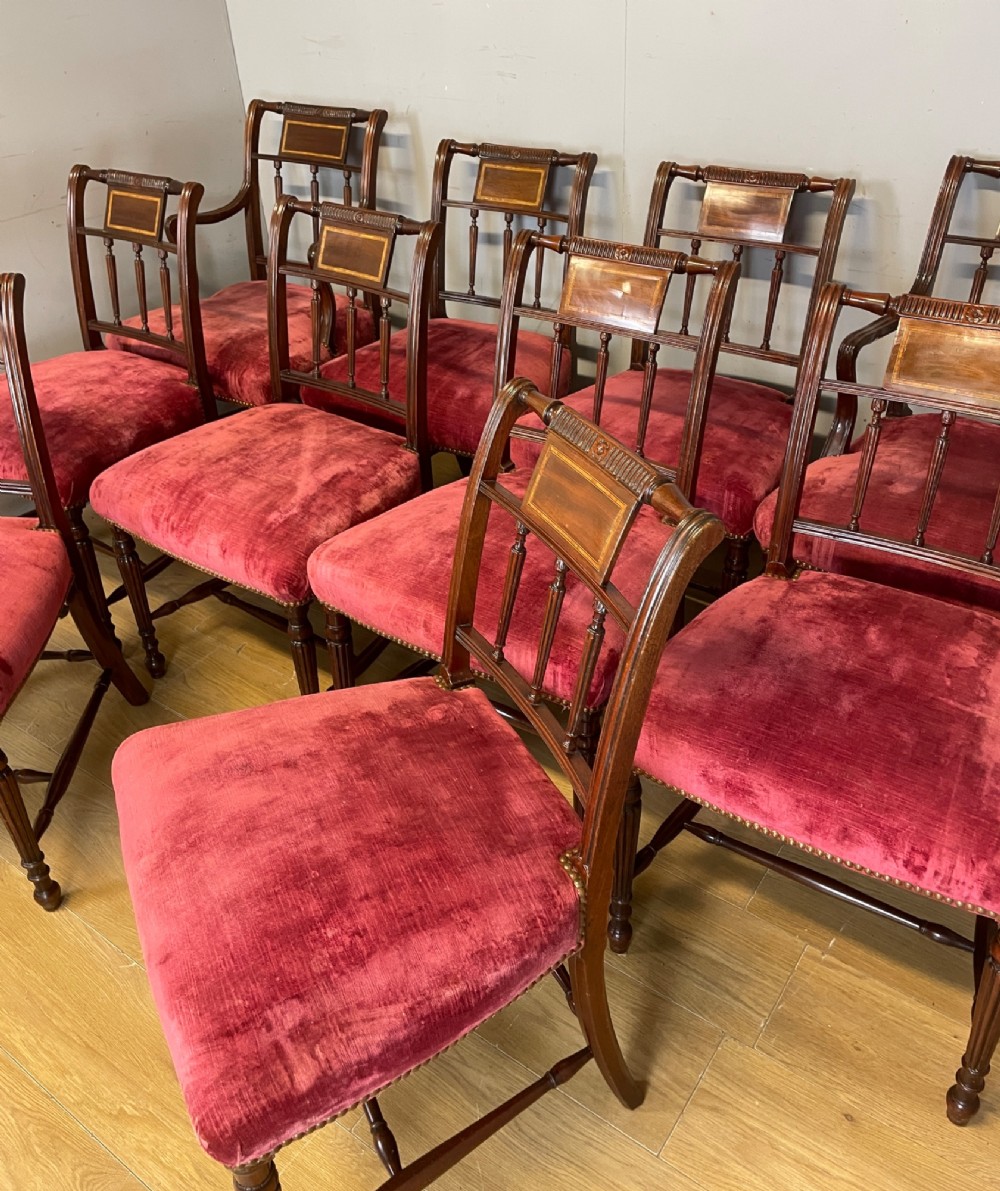 A set of ten nineteenth-century mahogany dining chairs featuring rectangular inlaid backrests, spindle uprights, and red velvet upholstered seats with brass stud detailing. View XIII