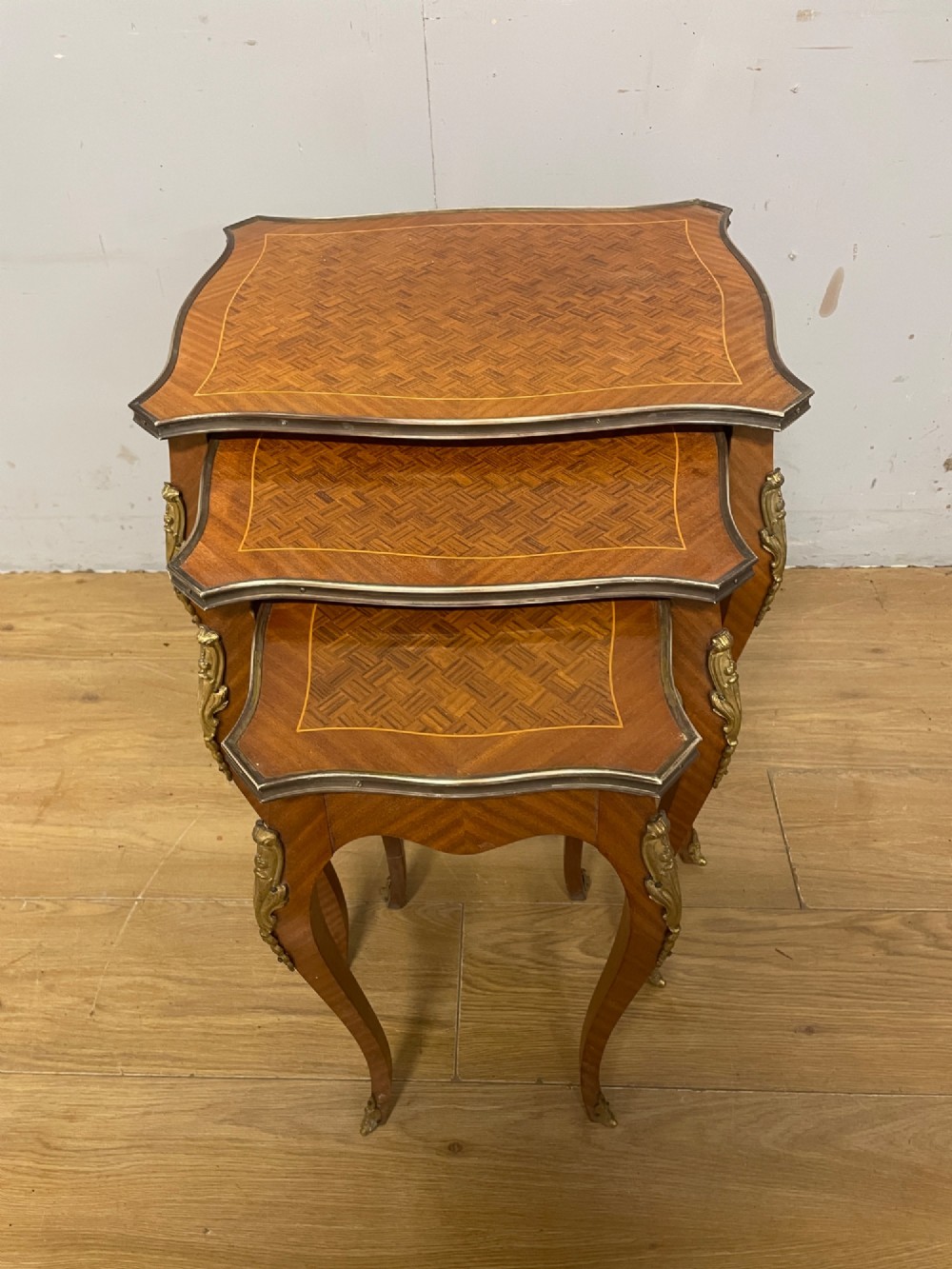 A set of three graduated French kingwood nesting tables featuring parquetry inlaid tops, cabriole legs, and gilded ormolu mounts. View II