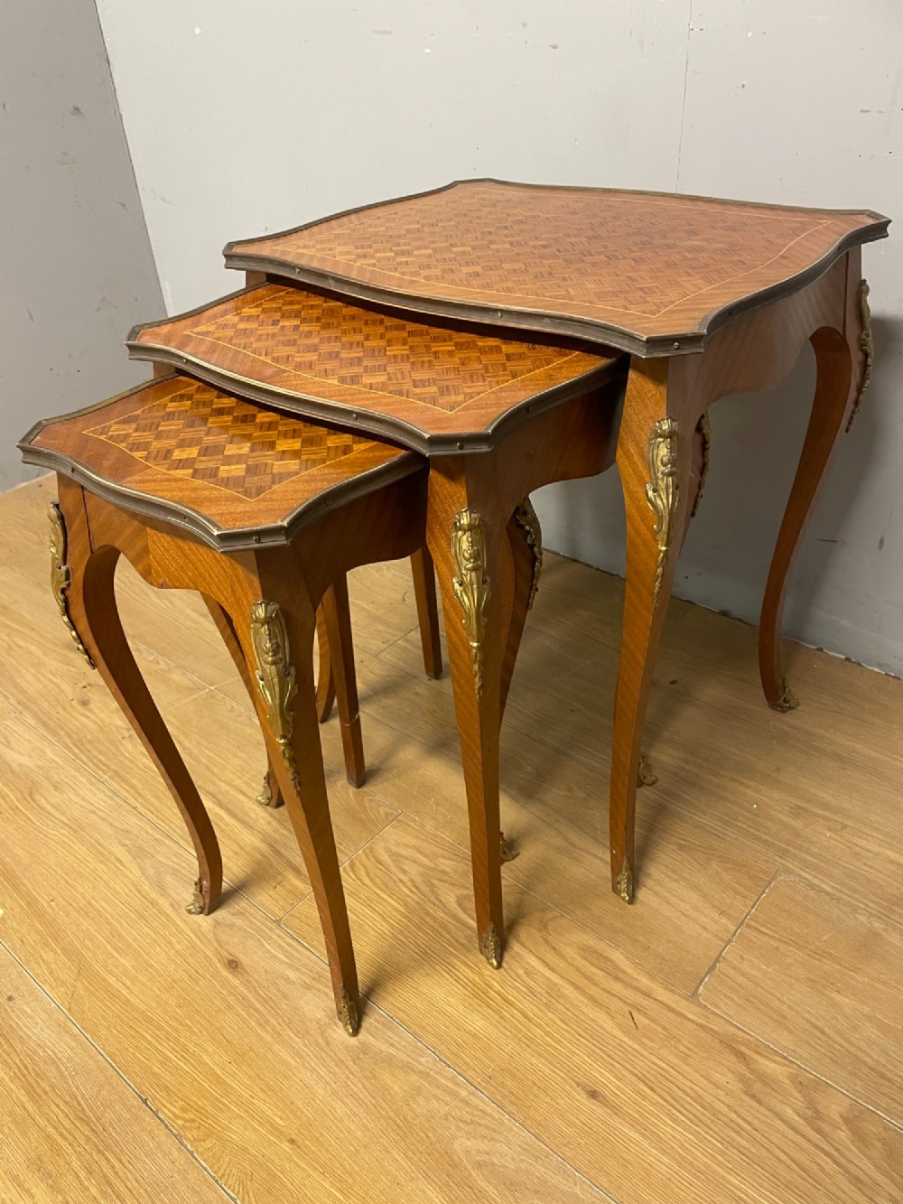 A set of three graduated French kingwood nesting tables featuring parquetry inlaid tops, cabriole legs, and gilded ormolu mounts. View III