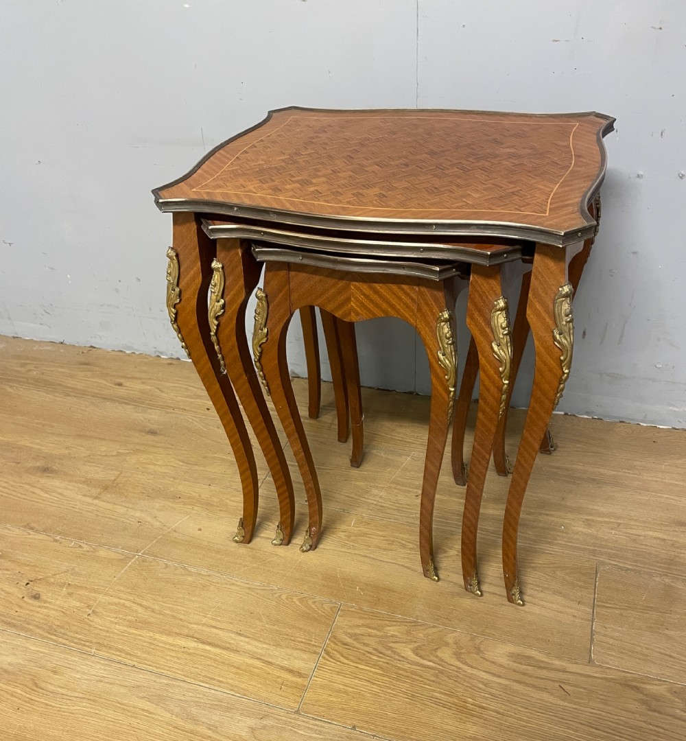 A set of three graduated French kingwood nesting tables featuring parquetry inlaid tops, cabriole legs, and gilded ormolu mounts. View IV